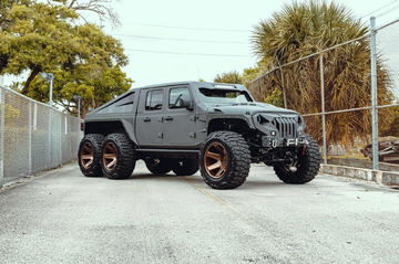 Vista lateral de un Jeep modificado con ruedas de gran tamaño y carrocería negra.