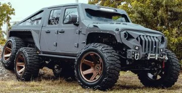 Vista lateral de un Jeep modificado con rines dorados y perfil alto