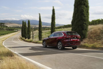 Vista dinámica de la trasera y lateral del Mazda CX-80 2024 en movimiento.