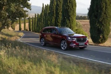 Vista dinámica del Mazda CX-80 2024 en movimiento, destacando su diseño lateral