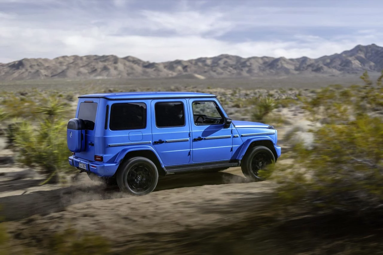 Vista dinámica del Mercedes Clase G 580 Eléctrico en acción sobre terreno arenoso.