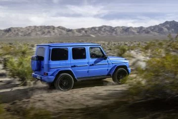 Vista dinámica del Mercedes Clase G 580 Eléctrico en acción sobre terreno arenoso.