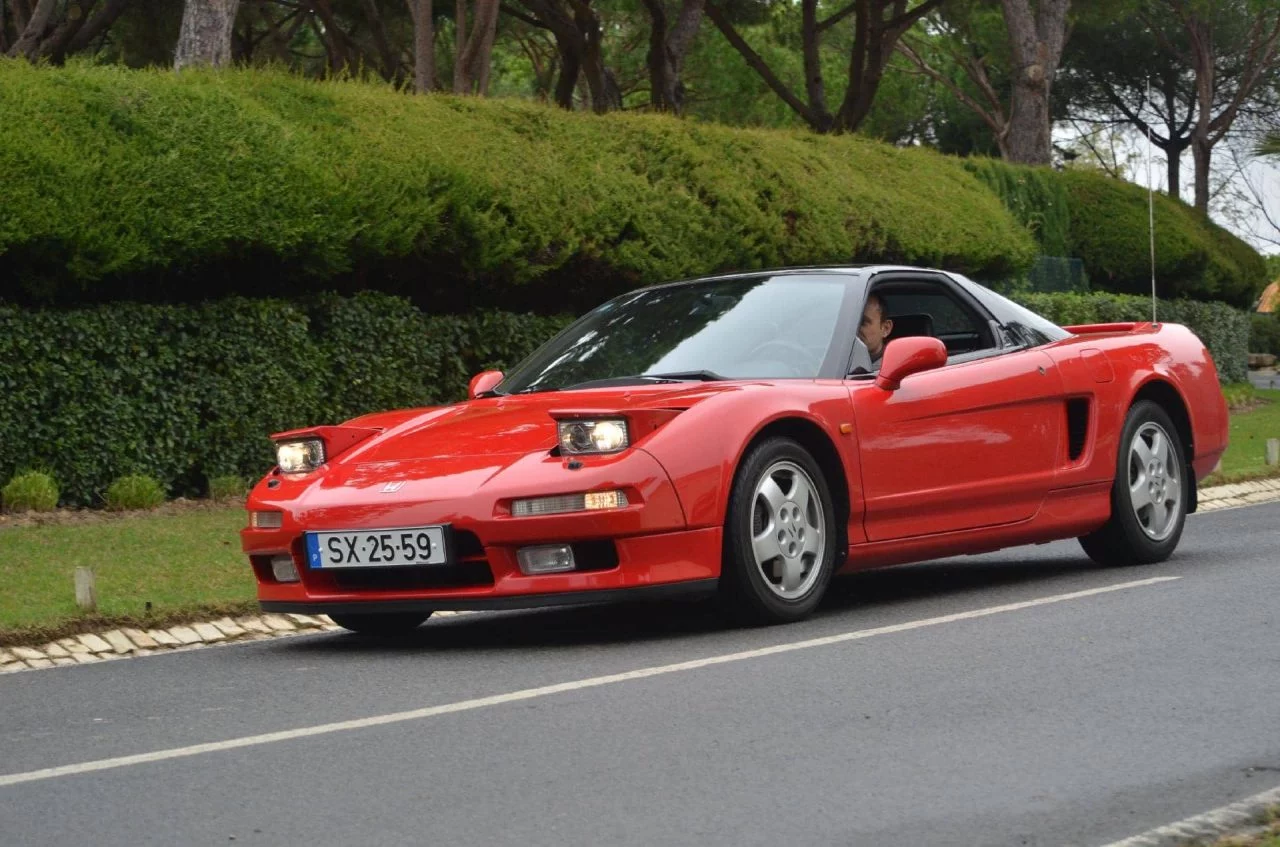 Honda NSX rojo perfilando su icónica silueta deportiva en movimiento.