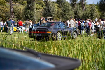 Clásico Porsche 911 en exhibición rodeado de entusiastas del motor.