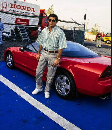 Leyenda del automovilismo posa junto al icónico Honda NSX rojo en el paddock.