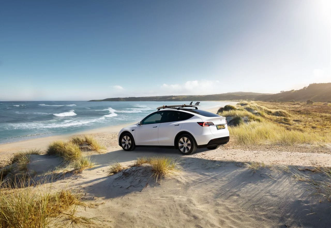 Vista lateral del Tesla Model Y 2024 estacionado en la playa.