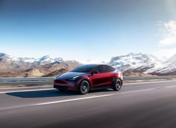 Vista lateral del Tesla Model Y 2024 en movimiento, capturando su perfil aerodinámico.