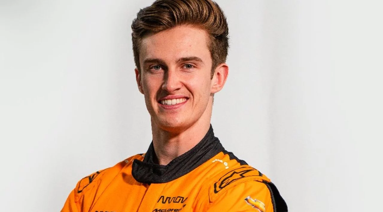 Piloto de Indycar con mono de competición McLaren, sonriente, enfoque de busto.