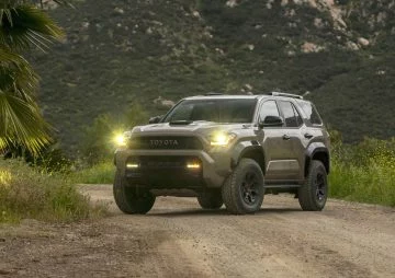 Vista frontal y lateral de Toyota 4Runner 2025 en camino de tierra, destacando su robustez y faros LED.