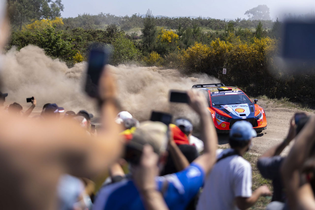 Vista trasera del vehículo en acción, envuelto en una nube de polvo en rally