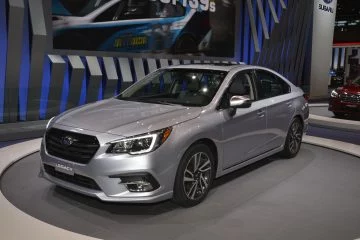 Vista lateral del Subaru Legacy elegante y pulido, destacándose en la exhibición.