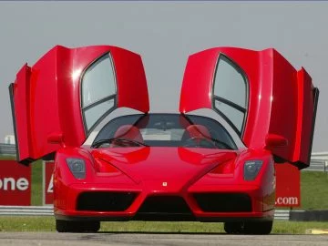 Vista frontal y lateral del icónico Ferrari Enzo, destacando su diseño aerodinámico y puertas tipo alas de gaviota.