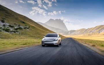 Tesla Modelo S avanzando por carretera montañosa, imponente diseño y dinamismo