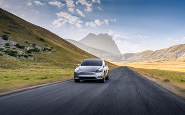 Tesla Modelo S avanzando por carretera montañosa, imponente diseño y dinamismo