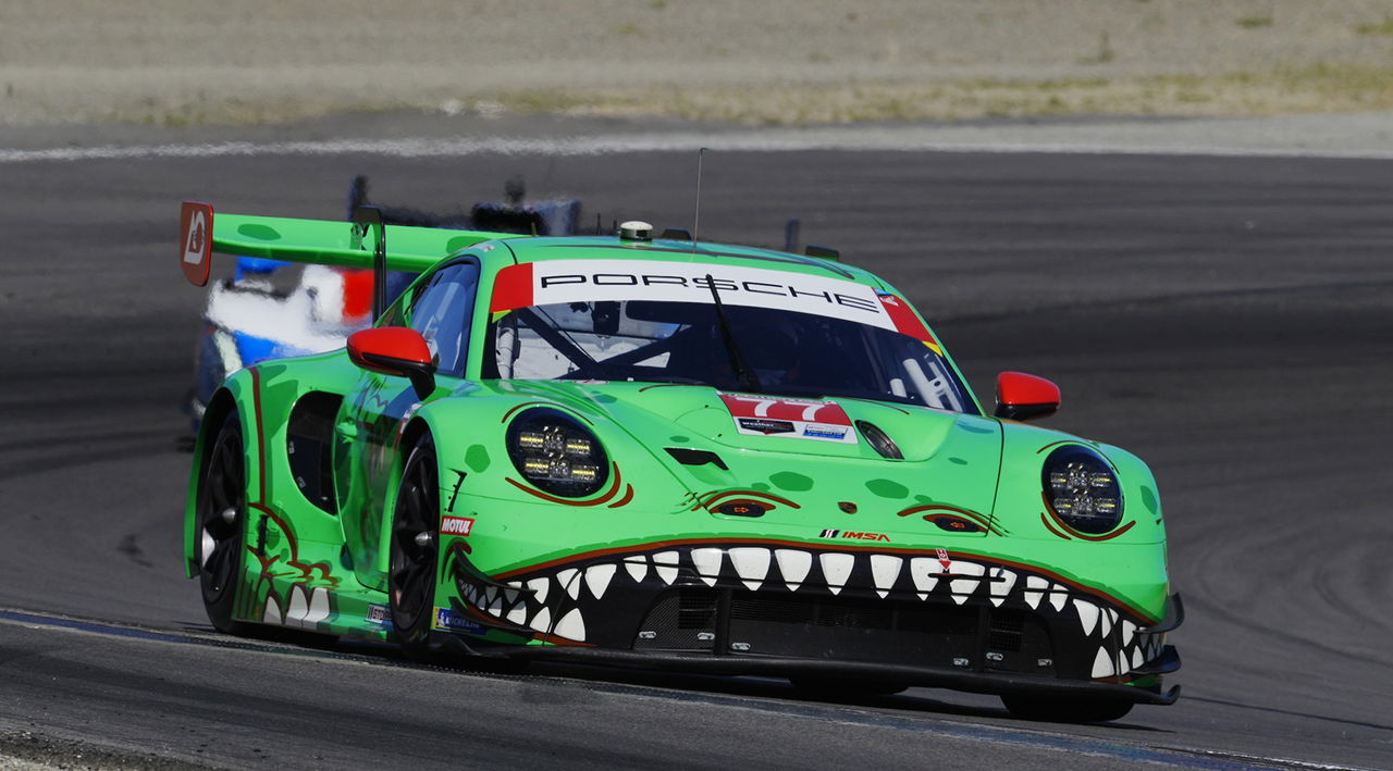 Vista dinámica del Porsche en acción en Laguna Seca, mostrando la parte delantera y lateral.