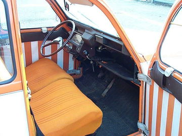 Vista parcial del icónico interior del Citroën 2CV, destacando su tapicería y diseño simple.