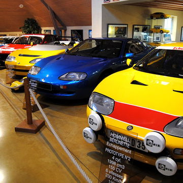 Vista frontal y lateral de una colección de deportivos clásicos en exhibición.