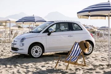 El Fiat 500 Dolcevita posa con estilo bajo el sol de la playa, evocando tiempos más sencillos y elegancia atemporal.
