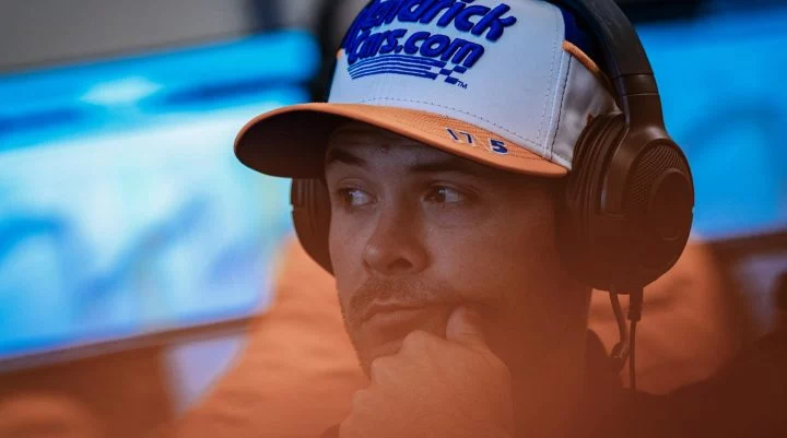 Kyle Larson en evento relacionado con el Indy 500, mostrando una gorra promocional.