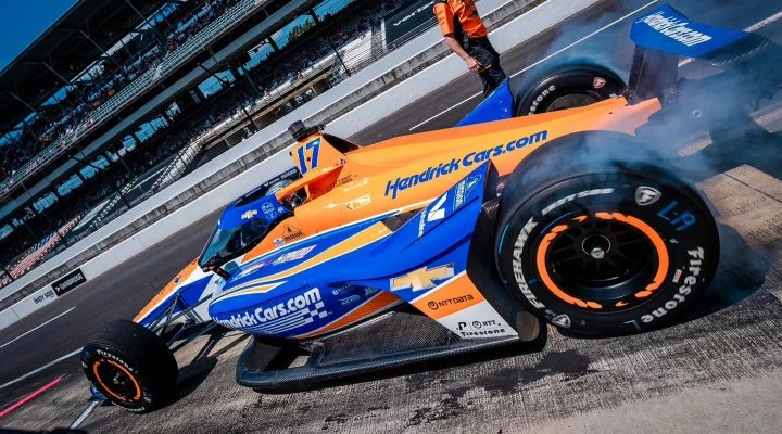 Kyle Larson pilotando su monoplaza en Indy 500, con atractiva decoración azul y naranja.