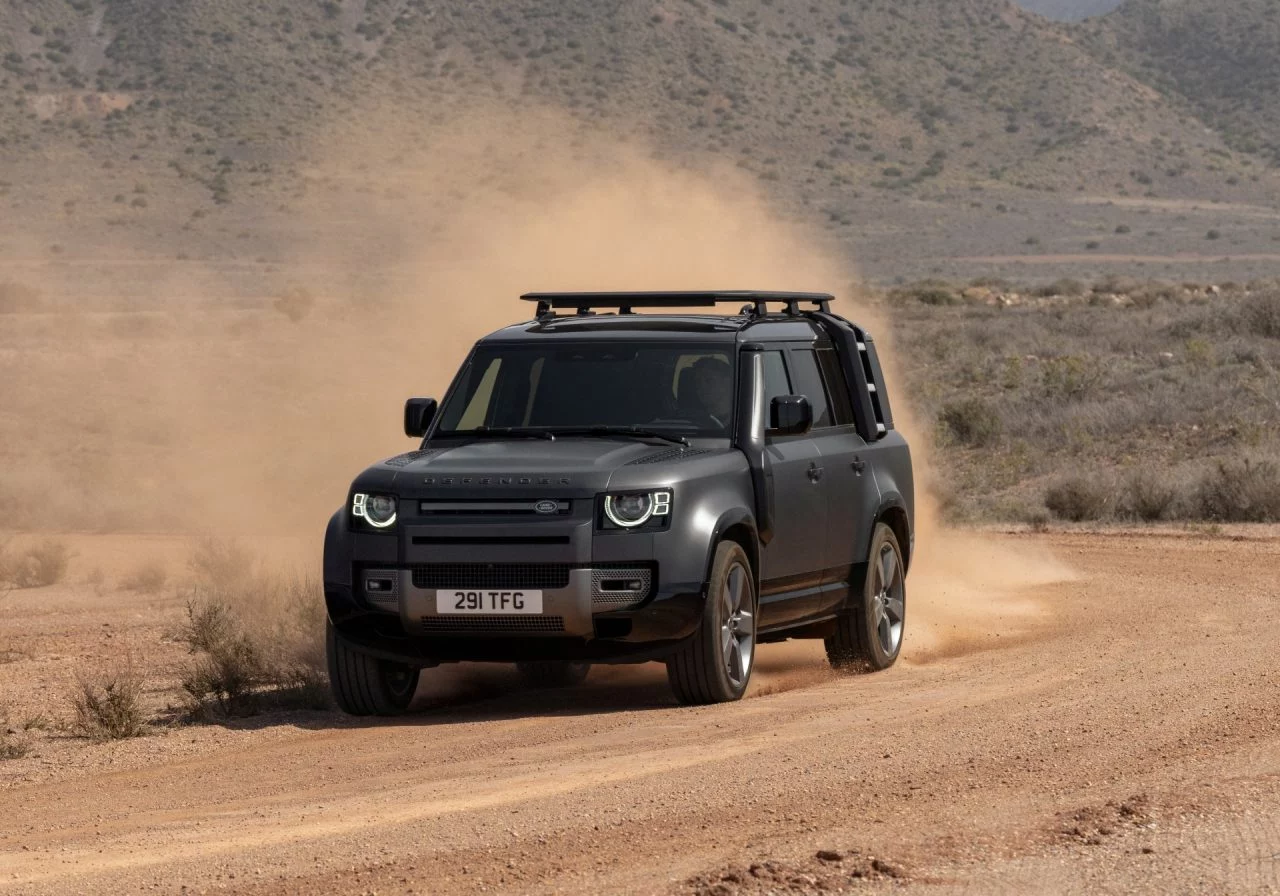 Vista dinámica del Land Rover Defender 2024 superando terreno árido.