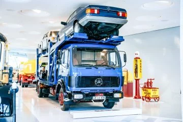Camión Mercedes 1624 utilizado para transporte de vehículos, exhibido en un ambiente museístico.