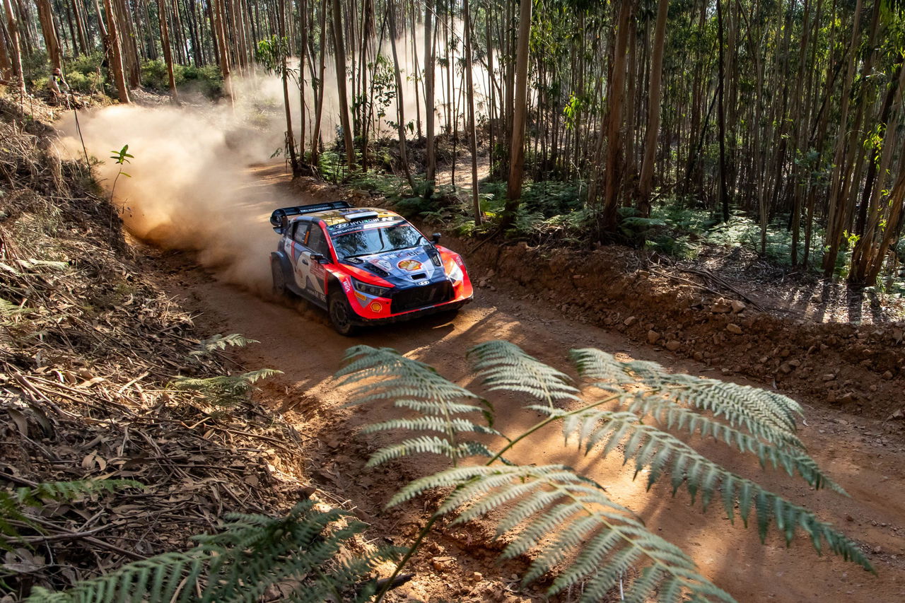 Vehículo de rally marca Hyundai en acción, derrapando en un tramo de tierra.