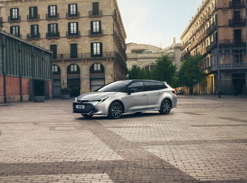 Vista dinámica del Toyota Corolla Touring Sports aparcado en una plaza urbana.