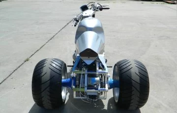 Perspectiva trasera y lateral de un trike mostrando su anchura y diseño de neumáticos.