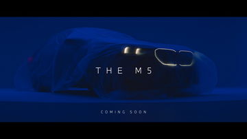 Vista anticipada de la delantera del nuevo BMW M5 bajo manto, prometiendo gran potencia.