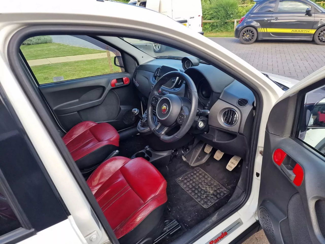 Vista interior del Abarth Panda con asientos deportivos rojos y volante deportivo