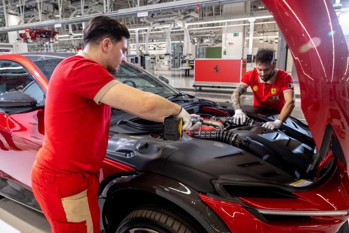 Operarios ensamblando un vehículo en la moderna línea de producción de Ferrari.