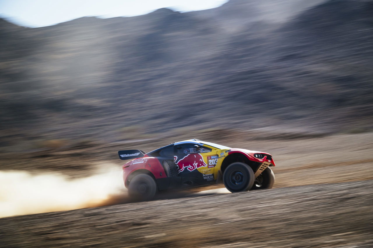 Vehículo de competición en acción durante el Rally Dakar, mostrando habilidades en terreno difícil.