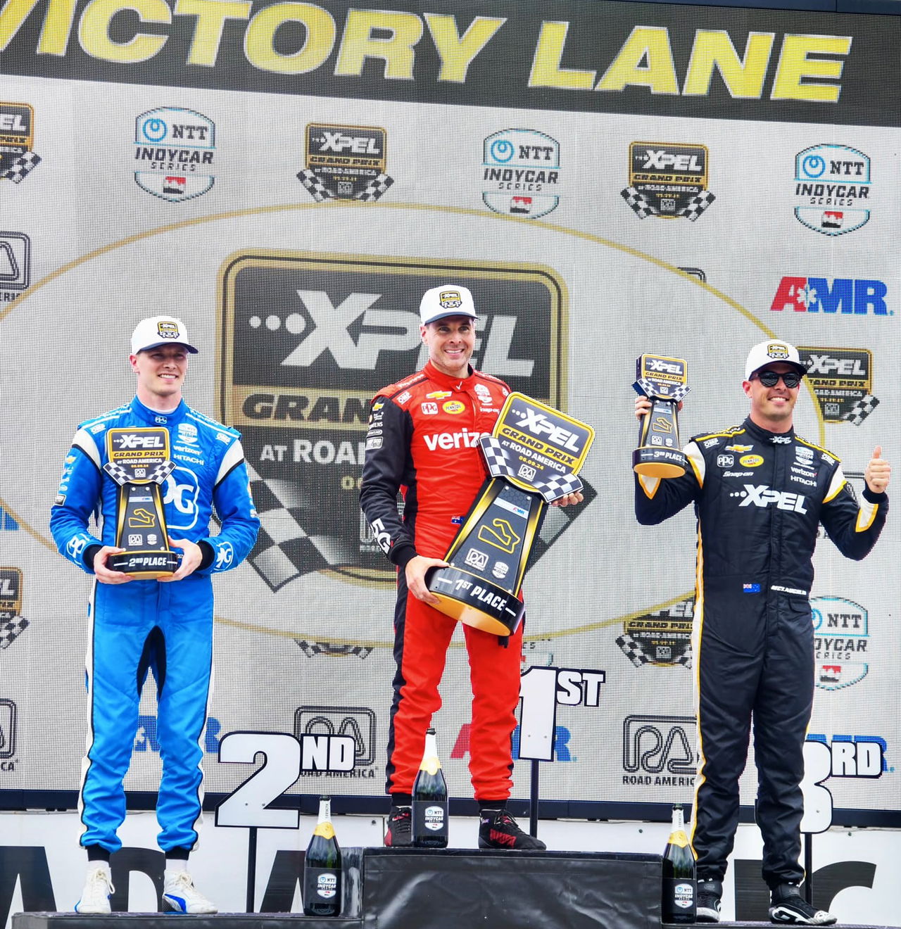 Pilotos celebrando en el podio tras una carrera en Road America, IndyCar.