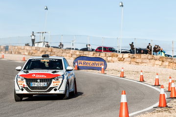 Vehículo de competición tomando curva en circuito de rally, demostrando agilidad y diseño aerodinámico.