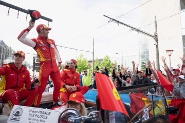 Piloto festeja victoria alzando un trofeo, un momento icónico en las carreras de resistencia.