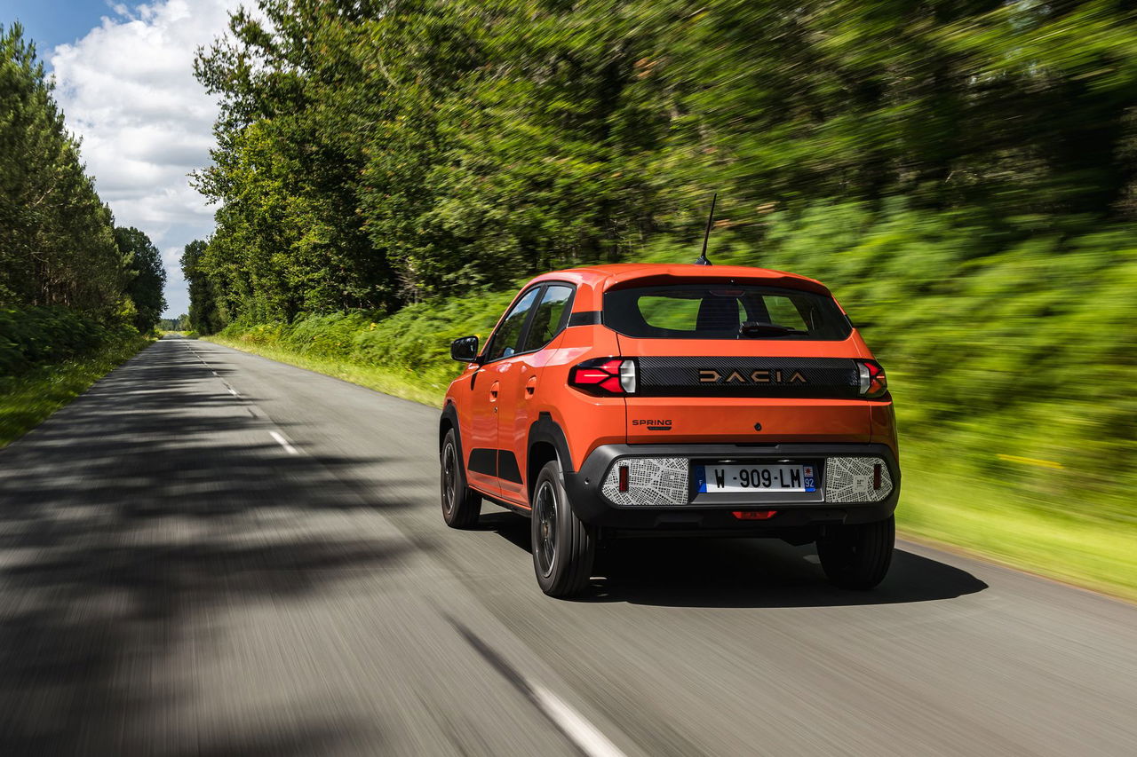 El Dacia Spring 2024 circula por una carretera rodeada de naturaleza.