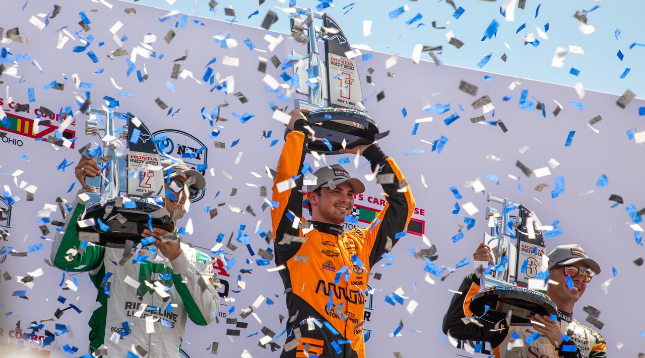 Patricio O'Ward celebra victoria en Mid-Ohio levantando trofeo.