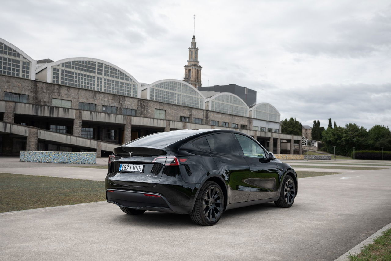 Vista lateral del Tesla Model Y LR AWD en movimiento, diseño aerodinámico y distintivo.