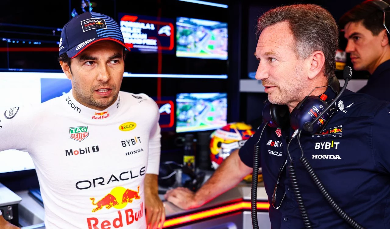 Checo Pérez conversando con personal de Red Bull Racing en el paddock.