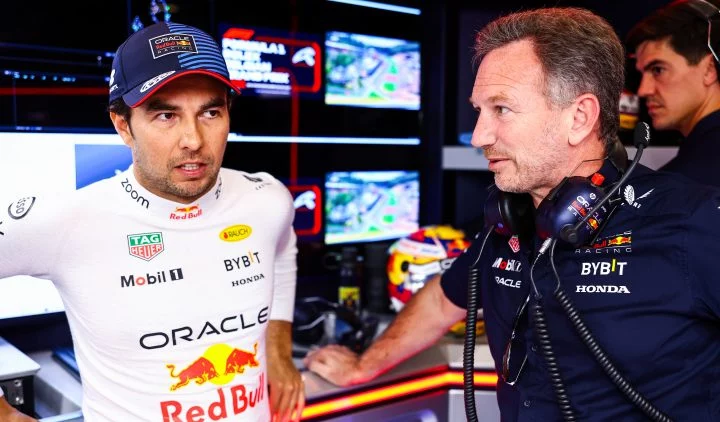 Checo Pérez conversando con personal de Red Bull Racing en el paddock.