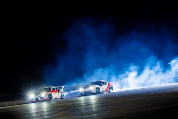 Dos vehículos realizando un drift sincronizado de noche