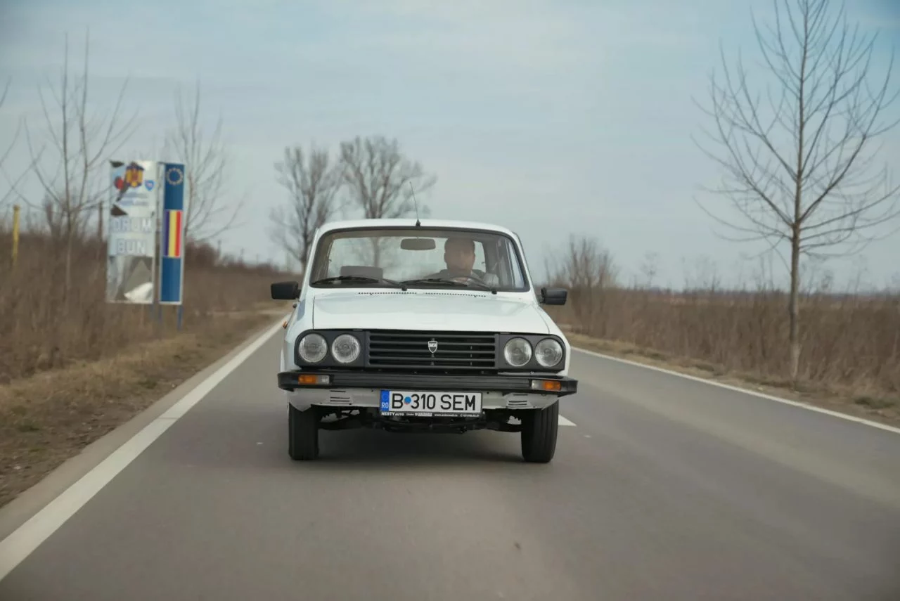 Vista frontal y lateral del Dacia 1310 en carretera, clásico del automovilismo.