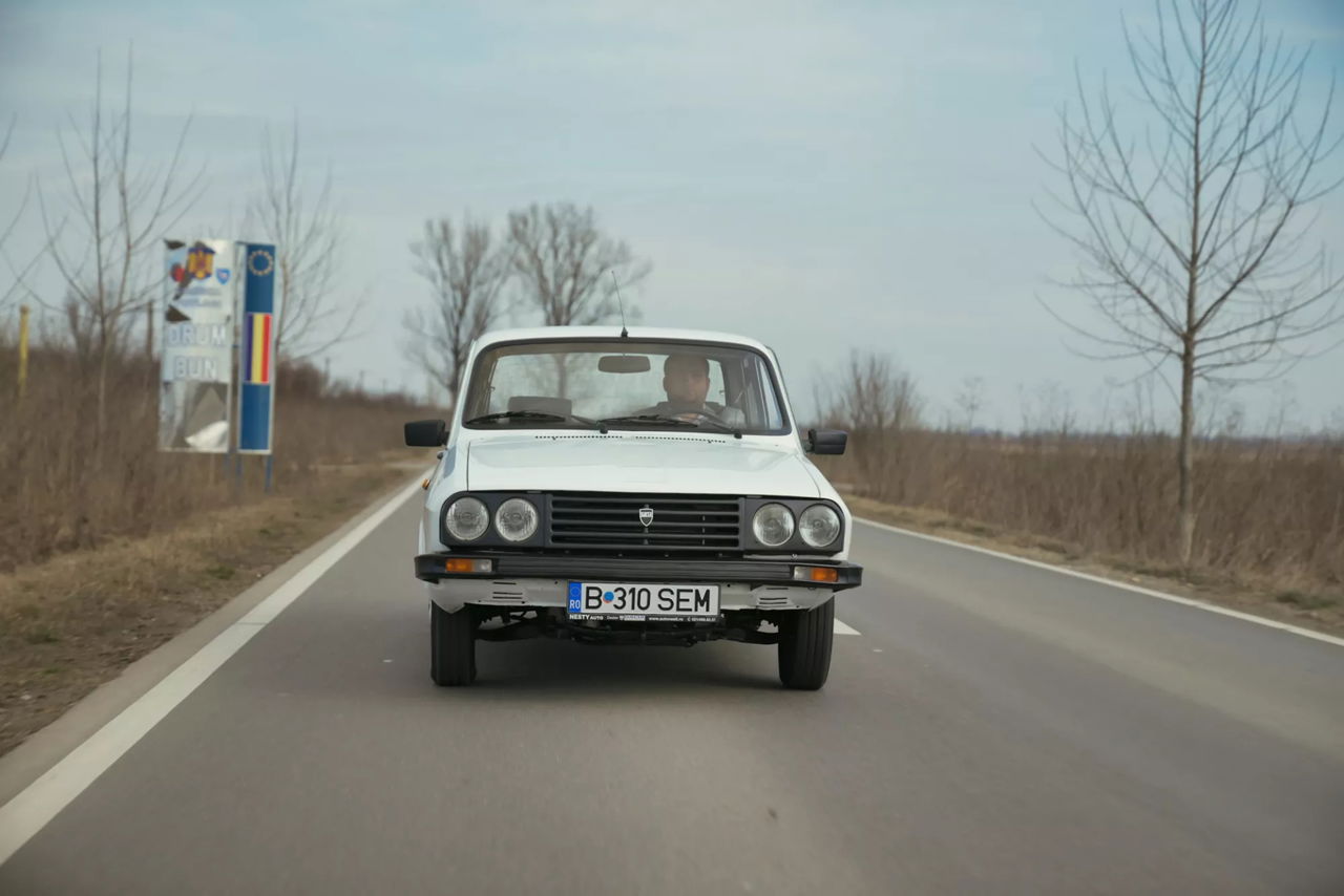 Vista frontal y lateral del Dacia 1310 en carretera, clásico del automovilismo.