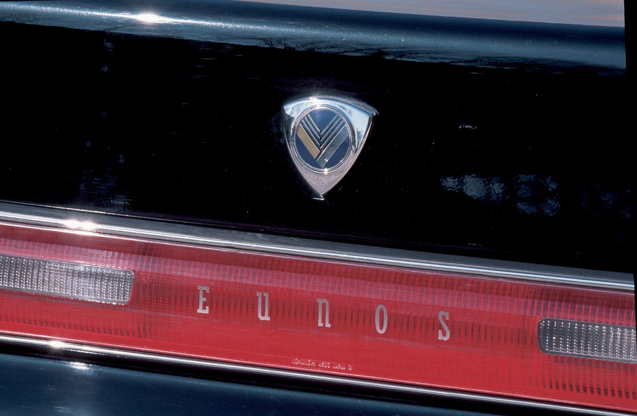 Detalle emblema Eunos Cosmo, reflejando exclusividad marca.