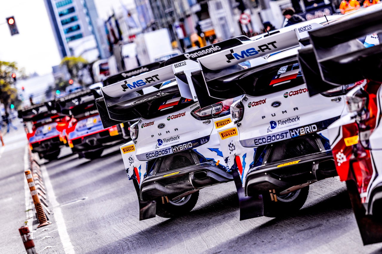 Vista trasera en fila de coches de rally WRC preparándose para la competencia.