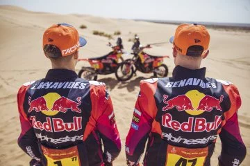 Pilotos de KTM con indumentaria oficial frente a sus motos en el desierto