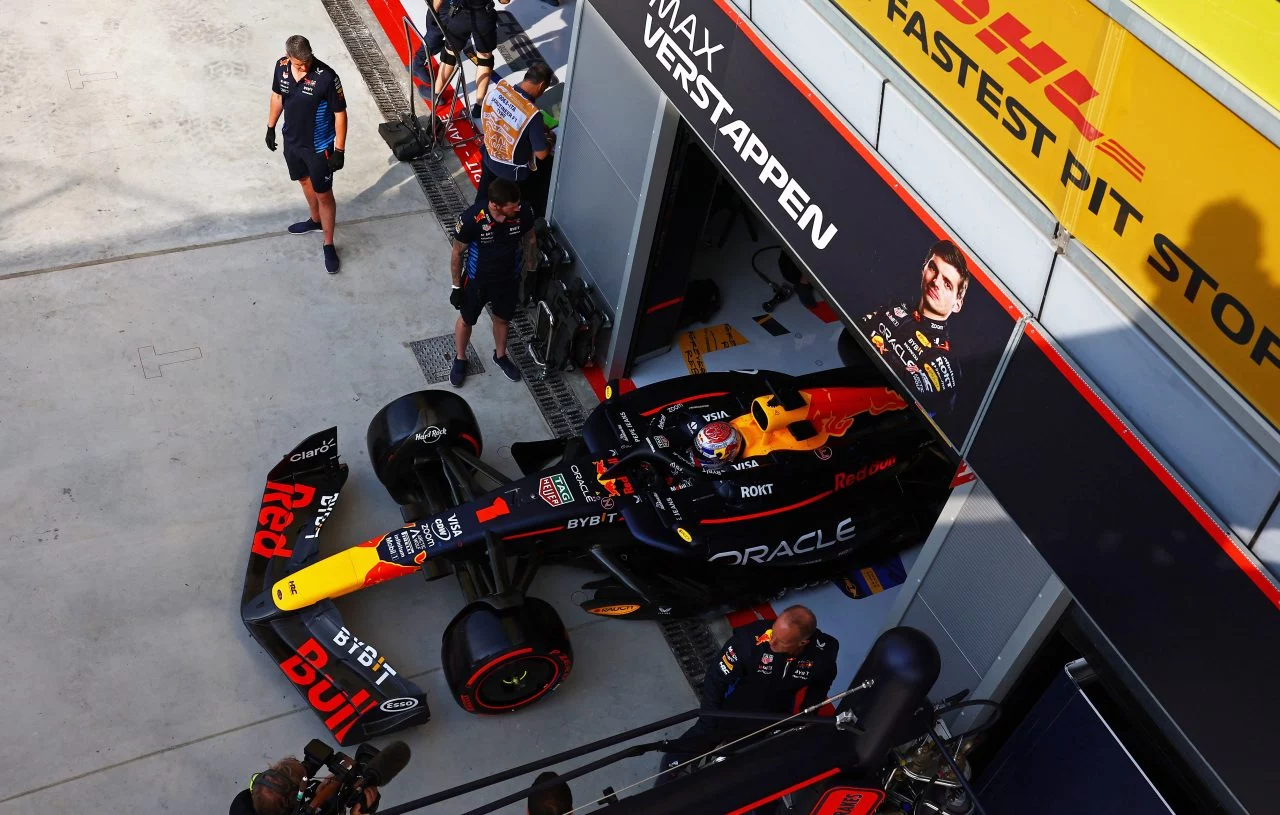 Vista lateral del monoplaza Red Bull en boxes, equipo trabajando en pit stop.