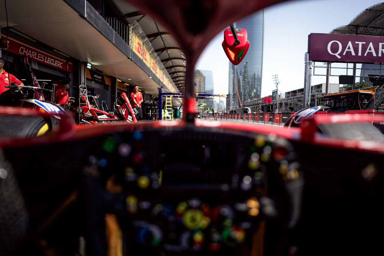 Cockpit de un monoplaza de F1, enfoque en el volante repleto de controles. Equipo en el fondo.