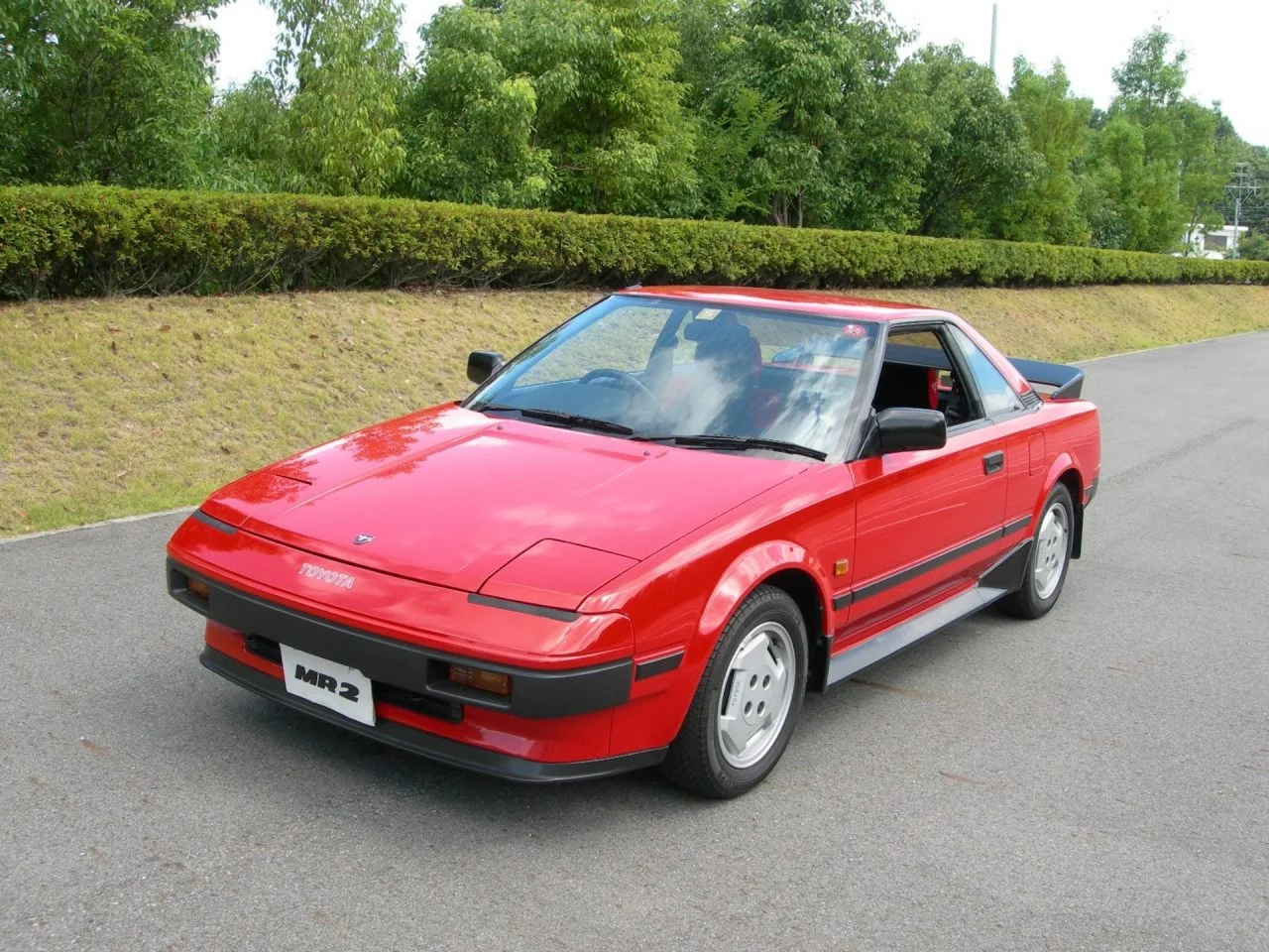 Un Toyota clásico de línea deportiva en un acabado rojo intenso.